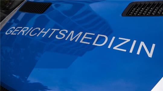 Ein Fahrzeug der Gerichtsmedizin steht vor einem Haus.