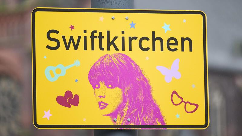 Eras-Tour in Hamburg: Das steckt hinter der Euphorie um Taylor Swift Das Ortsschild «Swiftkirchen» zu Ehren der Musikerin Taylor Swift hängt auf dem Heinrich-König-Platz. Mitte Juli kommt Musik-Superstar Taylor Swift zu Konzerten nach Gelsenkirchen.