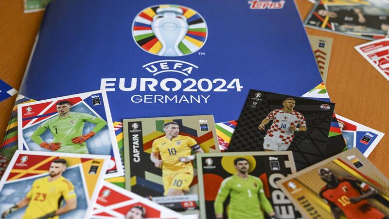 Das Sammelalbum Topps und einige Sticker zum Einkleben liegen zusammen auf einem Tisch. Im Stickerheft zur Fußball-EM 2024 fehlen Nationalspieler wie Manuel Neuer.