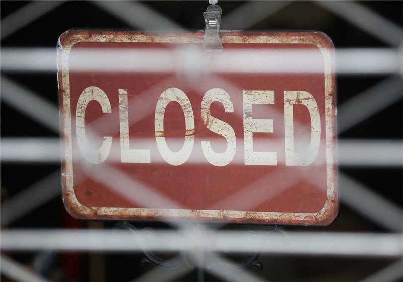 Das Schild "Closed" hängt hinter einem Rolltor am Eingang eines Geschäftes (Symbolbild). Foto: Oliver Berg/dpa