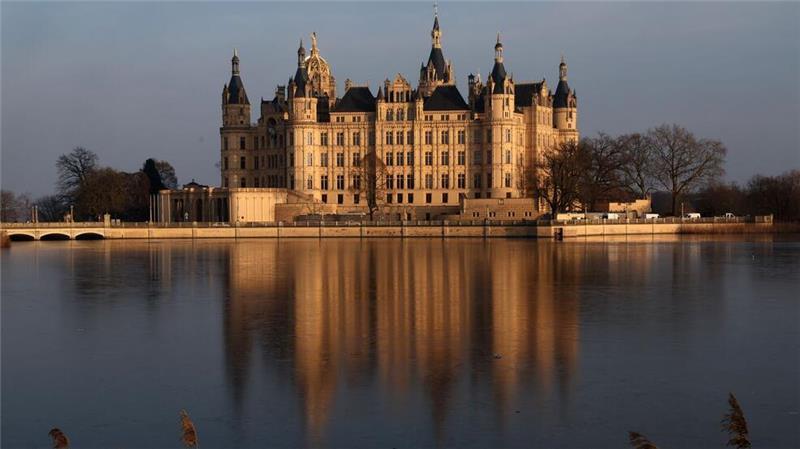 Das Schweriner Schloss spiegelt sich auf dem Eis auf dem Burgsee.