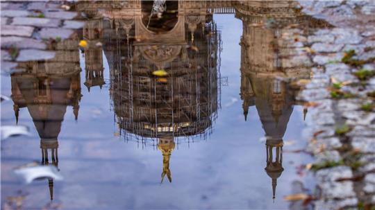 Das Schweriner Schloss spiegelt sich in einer Regenpfütze – graues, kühles und regnerisches Wetter zeigt den norddeutschen Sommer von seiner unfreundlichen Seite.