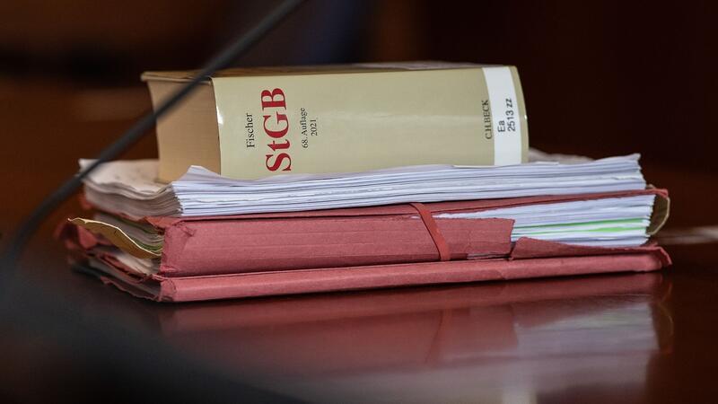 Tödlicher Raser-Unfall: Angeklagter bittet um Entschuldigung Das Strafgesetzbuch und Akten liegen in einem Gericht auf dem Tisch.