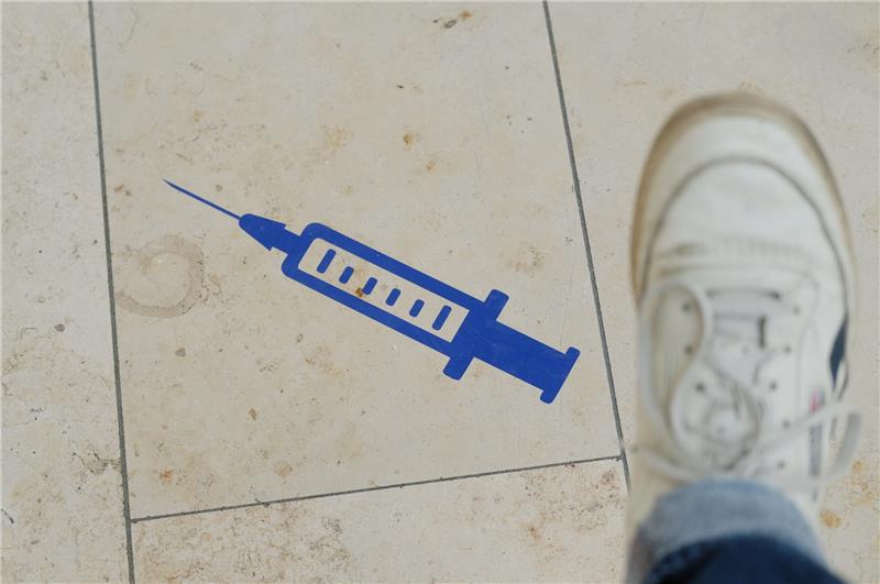 Das Symbol einer Spritze ist auf dem Boden aufgeklebt. Foto: Sebastian Willnow/dpa