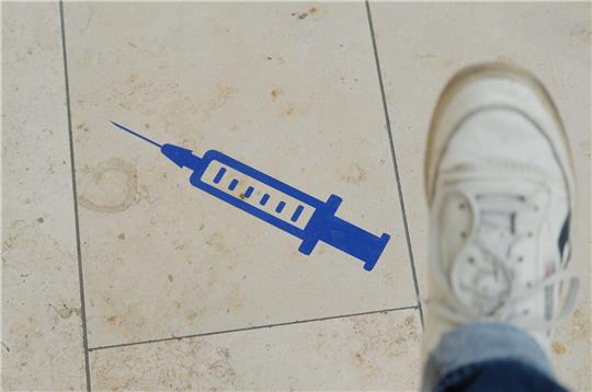 Das Symbol einer Spritze ist auf dem Boden aufgeklebt. Foto: Sebastian Willnow/dpa
