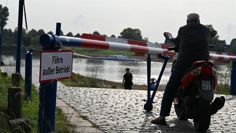 Das Warten auf die Fähre ist vergeblich: Ein Motorroller-Fahrer blickt einige Minuten auf den Rhein, dann kehrt er um und fährt davon. (Archivbild)