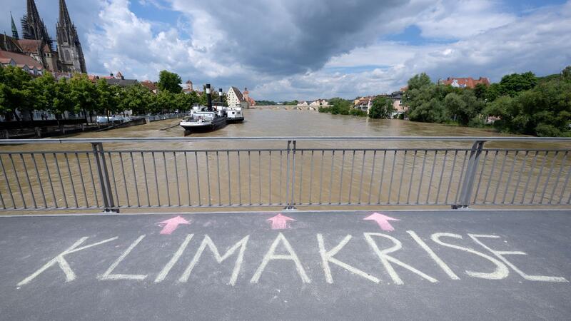 Das Wort „Klimakrise“ ist auf einer Brücke über der Donau in Regensburg zu lesen.