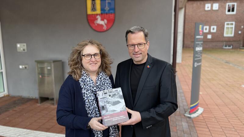 Debbie Bülau übergibt ihr erstes Buch-Exemplar an Landrat Kai Seefried.