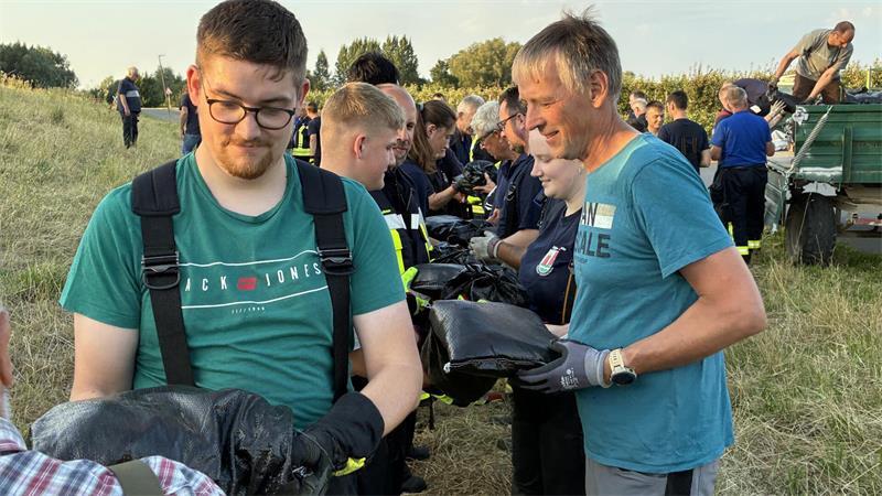 Deichverteidigungsübung: Einsatzkräfte der Ortsfeuerwehr Hollern-Twielenfleth und des Deichverbands der I. Meile Altenlandes bilden eine Menschenkette.