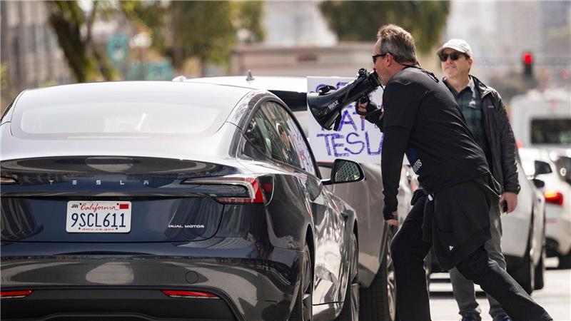 Demonstranten belästigen einen Tesla-Fahrer während einer Kundgebung vor einem Tesla-Händler in San Francisco.