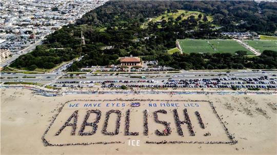 Demonstranten bilden ein menschliches Banner „We have eyes - no more lies - Abolish“ am Ocean Beach in San Francisco während eines Protests gegen die US-Einwanderungsbehörde ICE.