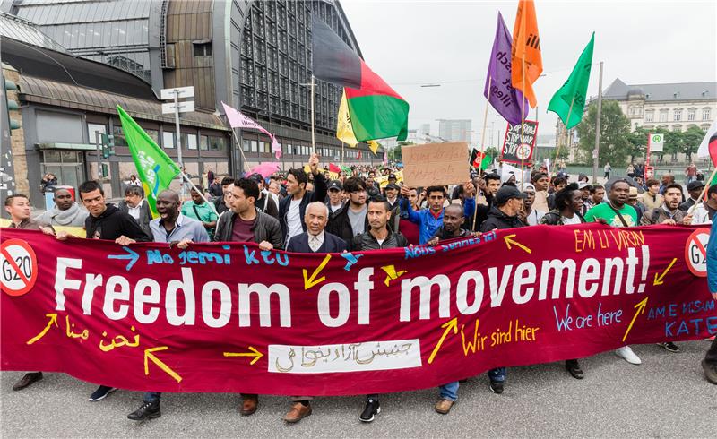 Demonstranten demonstrieren vor dem Rathaus in Hamburg hinter einem Transparent mit der Aufschrift „Freedom of movement!“ gegen die Flüchtlingspolitik der G20-Staaten. Foto: Markus Scholz/dpa