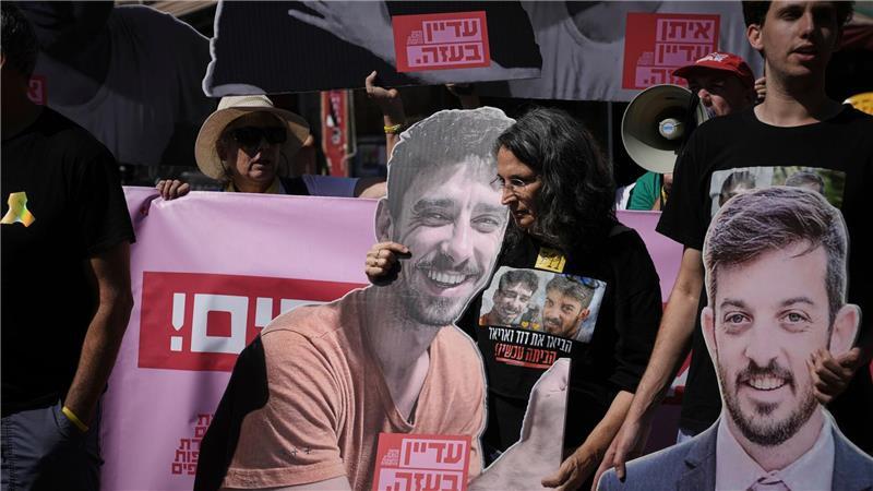 Demonstranten halten bei einem Protest gegen die Offensive in der Stadt Gaza Fotos von Geiseln. 