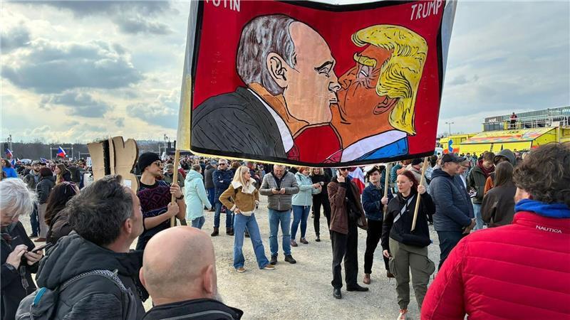 Demonstranten halten bei einer Kundgebung des Bündnisses „Eine Million Augenblicke für Demokratie“ ein Banner, auf dem sich stilisiert US-Präsident Trump und Russlands Präsident Putin küssen.