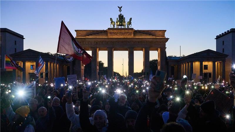 Bilder des Tages Demonstranten halten ihre Handys mit Taschenlampen vor dem Brandenburger Tor in die Luft. Die Demonstration unter dem Motto „Brandmauer hoch! Wir sind das Stadtbild“ bezieht sich auf eine Äußerung von Bundeskanzler Merz im Zusammenhang mit der Migrationspolitik.