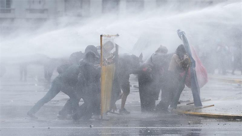 Demonstranten in Buenos Aires suchen Deckung, während die Polizei bei einer regierungskritischen Demonstration einen Wasserwerfer einsetzt.