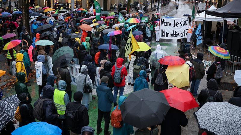 Demonstranten laufen in Hamburg durch den Regen. 