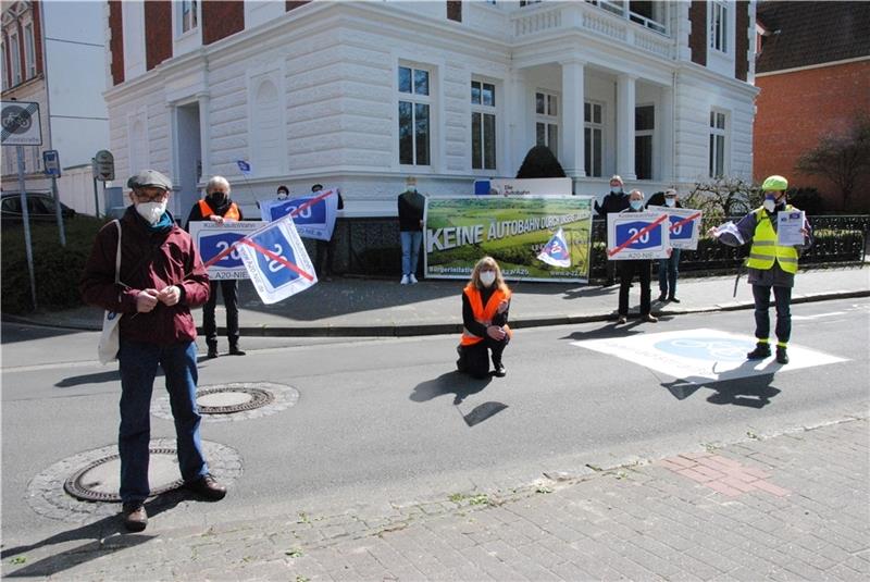 Demonstranten stehen mit ihren Plakaten gegen die Autobahn vor dem Haus der Autobahnplaner in Stade. Foto: Stief