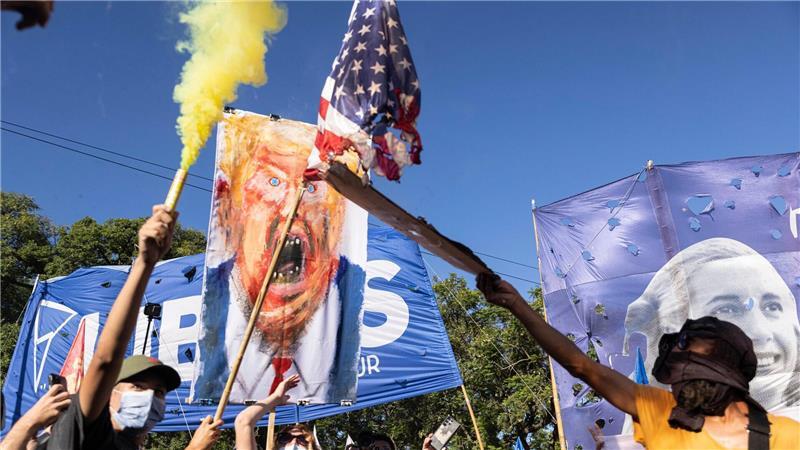 Demonstranten zünden mit einer Fackel eine amerikanische Fahne an.