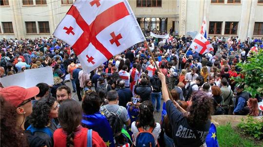 Demonstrantinnen und Demonstranten schwenken vor dem Parlamentsgebäude in Tiflis georgische Nationalflaggen.
