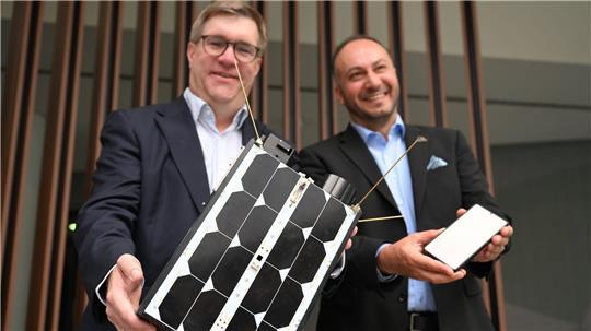 Demonstrativ gute Laune von O2-Manager Jörg Kablitz und OQ-Chef Omar Qaise, die bei der Vorstellung ihres Vorhabens ein Modell eines Satelliten dabeihatten. 