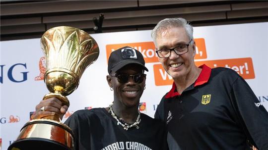 Dennis Schröder (l) und Basketball-Bundestrainer Gordon Herbert mit dem WM-Pokal.