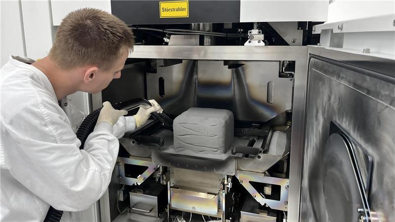 Denys Volchek saugt Titanpulver ab. Dann holt er den „Pulverkuchen“ aus dem Elektronenstrahlschmelzer, in dem die Implantatkörper stecken.
