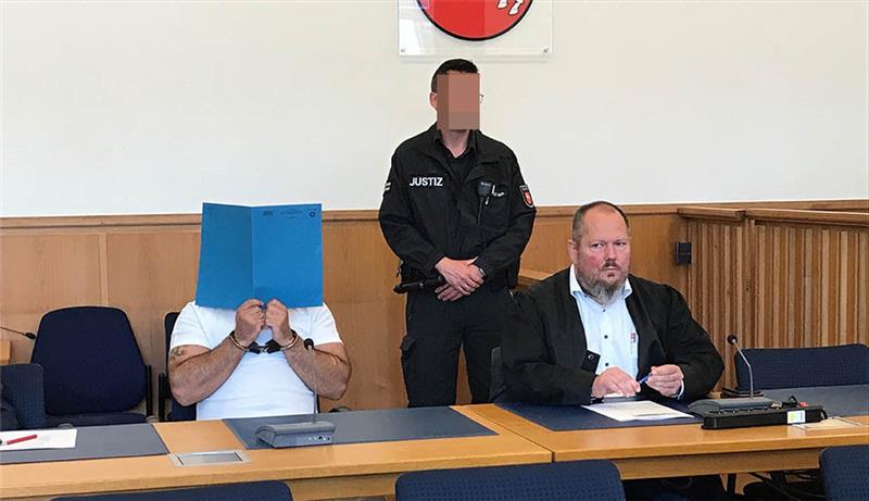„Imbiss-Mord“: 28-jähriger Stader zu lebenslanger Haftstrafe verurteilt Der 28-Jährige (Gesicht durch blaue Mappe verdeckt), der im September vergangenen Jahres einen 23-Jährigen am Stadthafen in Stade erschossen und zwei weitere Männer schwer verletzt hat, wurde wegen Mordes verurteilt. Foto: Helfferich