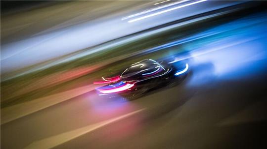 Ein Auto fährt bei Nacht auf einer Straße.