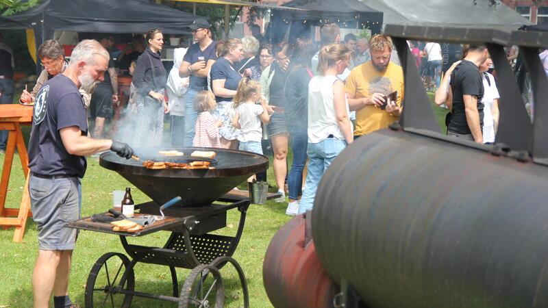 Der Andrang ist groß auf dem Barbecue-Festival. Rechts ist der rauchende Smoker der Veranstalter zu sehen, links bereitet Ronny Wolf vom befreundeten „BBQ MV“ aus Mecklenburg-Vorpommern Speisen vor.