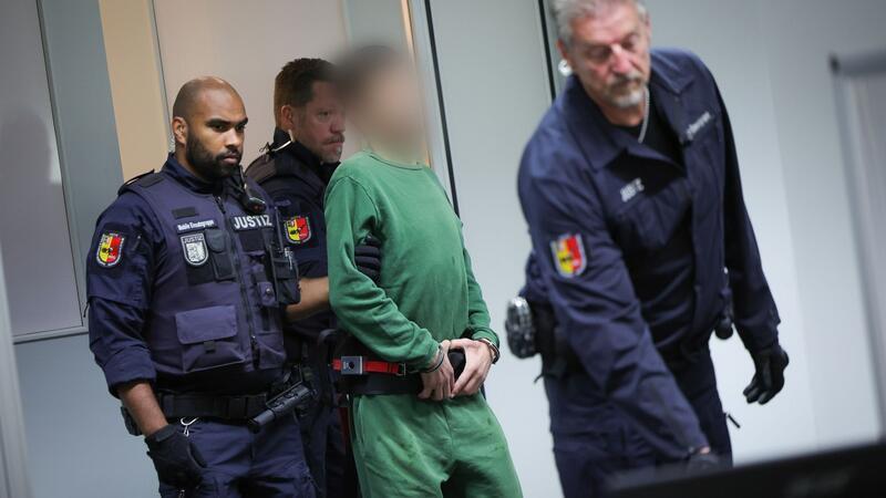 Der Angeklagte Ibrahim A. (M) wird in Handschellen in den Gerichtssaal im China Logistic Center gebracht.