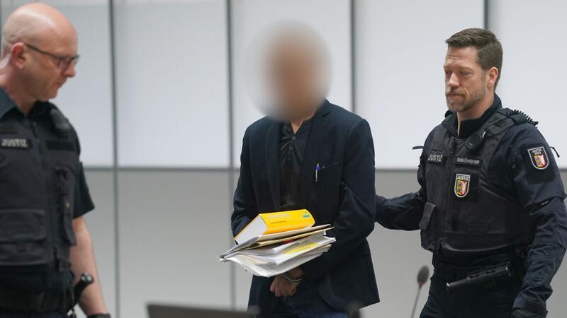 Der Angeklagte (M) wird zu Beginn des Prozesses von Justizbeamten in den Gerichtssaal des Landgerichts Itzehoe im China Logistic Center gebracht.