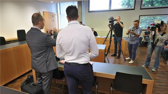Der Angeklagte (Mitte) steht mit seinem Anwalt im Verhandlungssaal.