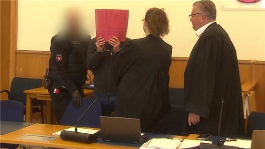 Der Angeklagte Mustafa M. schützt sein Gesicht mit einem Aktendeckel. Seine Verteidiger Dirk Meinicke (rechts) und Dina Busse nehmen ihn in Empfang.