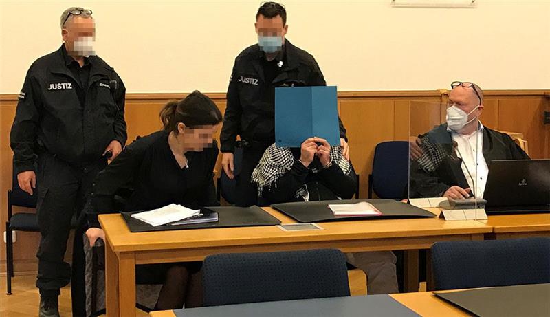 Der Angeklagte im Prozess um den Stader "Imbiss-Mord" hält sich eine Mappe vors Gesicht. Foto: Helfferich