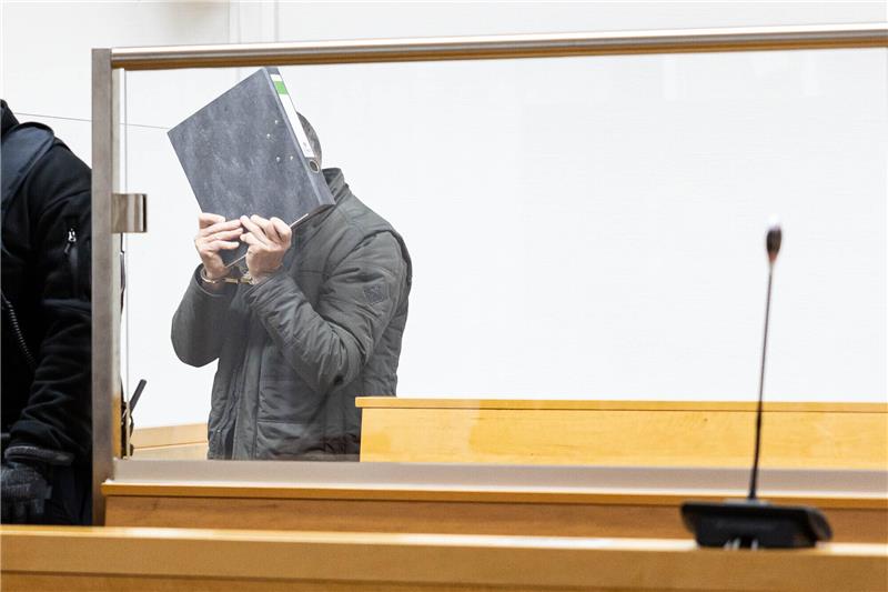 Elf Jahre Haft für Tötung von Ehefrau - Tochter weint im Gerichtssaal Der Angeklagte kommt zum Prozessauftakt in einen Saal vom Landgericht Hannover und hält sich einen Aktenordner vor das Gesicht. Ihm wird vorgeworfen, im Juni 2022 in Hannover mit einem Küchenmesser auf seine Ehefrau eingestochen und sie getötet zu haben. Anschließend soll er auf einen selbst herbeigerufenen Polizisten eingestochen haben. (zu dpa: «Kein Mord: Gericht wertet tödliche Messerattacke als Affekttat») Foto: Michael Matthey/dpa