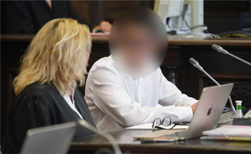 Der Angeklagte (r) sitzt zu Beginn des Prozesses wegen Mordes im Sitzungssaal im Strafjustizgebäude.