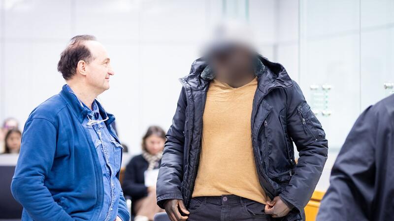 Der Angeklagte (r) steht im Gerichtssaal.