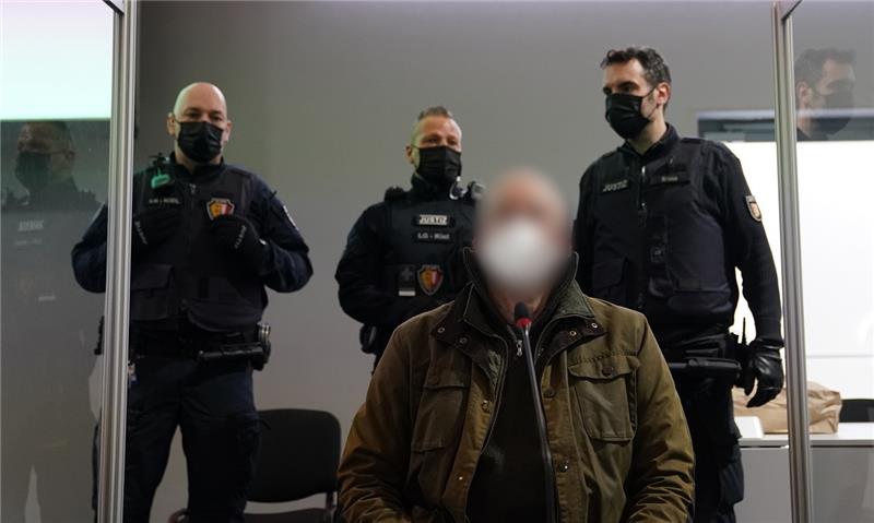 Der Angeklagte sitzt bewacht von Justizbeamten zu Beginn des Prozesses wegen eines Dreifachmordes im Sitzungssaal des Landgerichts. Foto: Marcus Brandt/dpa