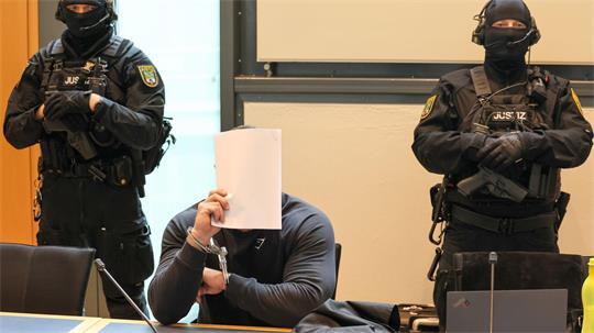 Der Angeklagte sitzt im Gerichtssaal des Landgerichts Magdeburg zwischen zwei Justizbeamten.
