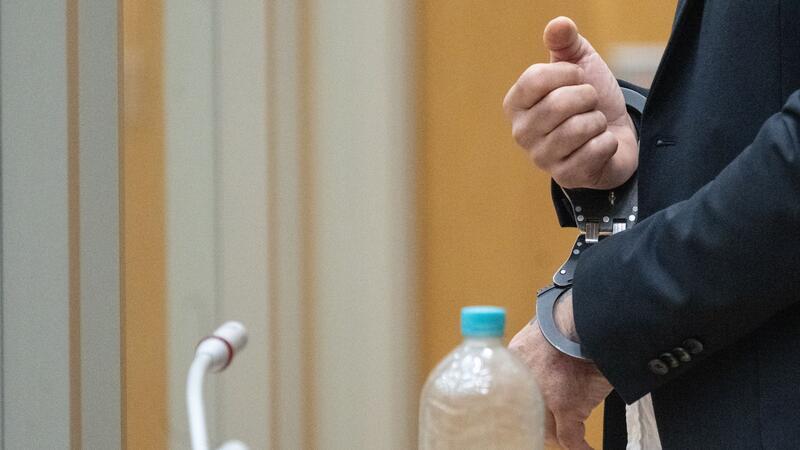 Lange Haftstrafe für Angeklagten in „Reichsbürger“-Prozess Der Angeklagte steht in Handschellen in einem Saal des Oberlandesgerichts Stuttgart.