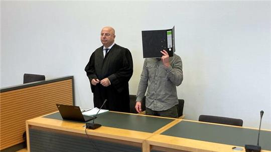 Der Angeklagte steht neben seinem Anwalt im Gerichtssaal.