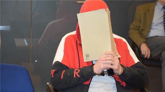 Der Angeklagte verdeckt sein Gesicht hinter Büropappe. Die Staatsanwaltschaft wirft dem 43-Jährigen vor, im August 2022 einen Mann an einem Baggersee bei Buxtehude erschossen zu haben.