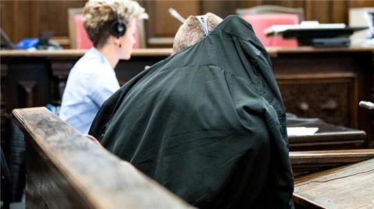 Der Angeklagte verdeckt sein Gesicht mit einer Jacke.