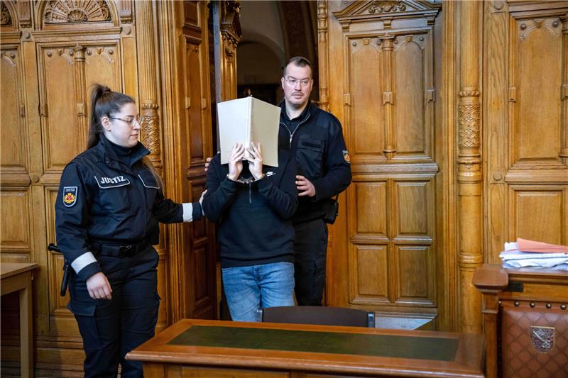Der Angeklagte wird in den Gerichtssaal geführt. Rund neun Monate nach dem gewaltsamen Angriff mit einer Armbrust in einem Bremerhavener Gymnasium werden am Landgericht Bremen die Plädoyers und das Urteil erwartet. Wegen versuchten Mordes angeklagt ist ein 21-jähriger ehemaliger Schüler der Schule. Foto: Sina Schuldt/dpa