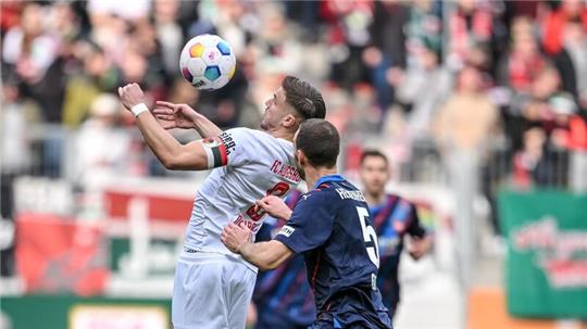 Der Augsburger Ermedin Demirovic (l) behauptet den Ball gegen Heidenheims Benedikt Gimber.