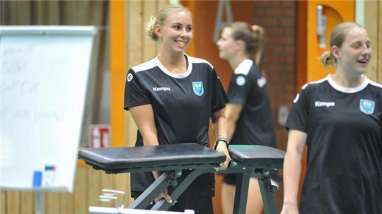 Oliwia Kamisnka grinst und schleppt eine Hantelbank durch die Halle Nord.