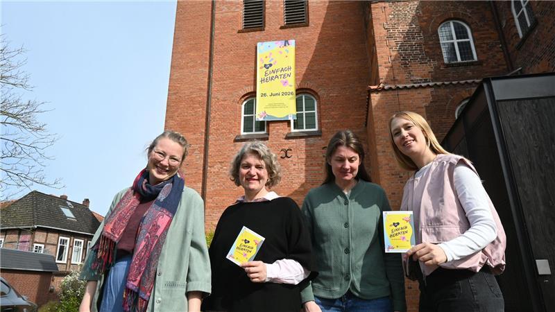 Der Banner hängt bereits am Turm: Mira Neckel, Dorlies Schulze, Heike Kircher und Vikarin Marielle vor dem Turm der Liebfrauenkirche in Horneburg für die Aktion „Einfach Heiraten“ (von links).