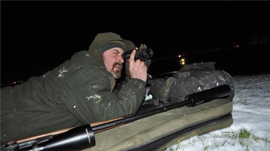 Der Berufsjäger Jens Kleinekuhle liegt in Blexen bei Schnee und Eis auf dem Deich und hält nach Füchsen Ausschau. Fast jede Nacht ist er unterwegs.Foto: Heilscher