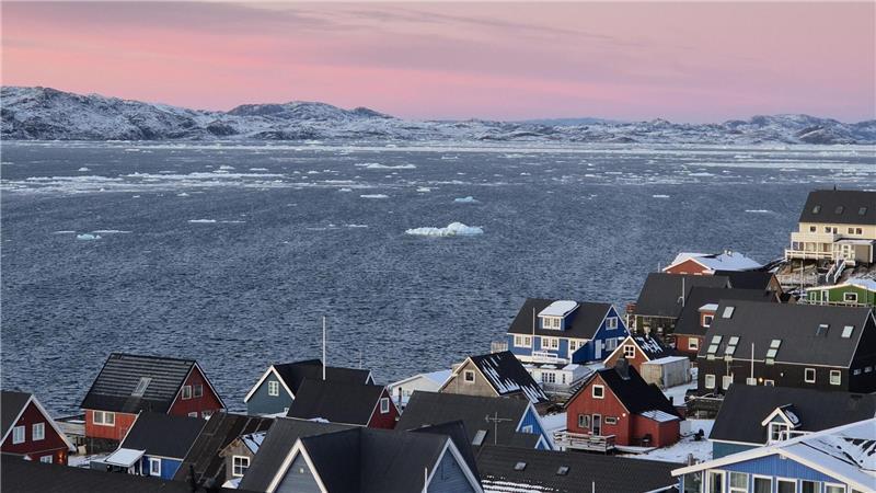 Der Blick aus Norja Walthers Studierendenwohnheim in Nuuk: bunte Holzhäuser, das weite Meer und schneebedeckte Berge im arktischen Licht.